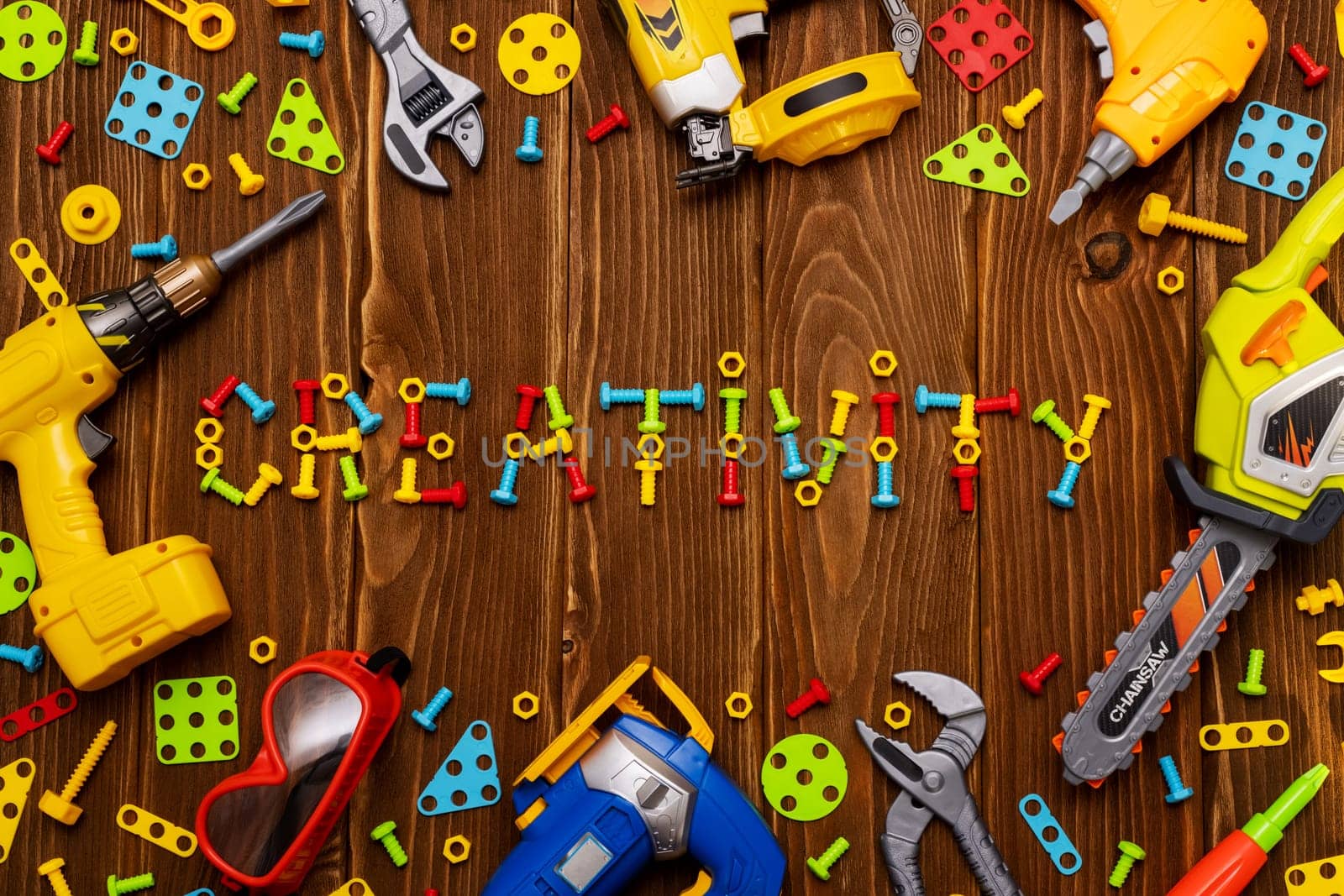 Toy tools, bolts and nuts with text CREATIVITY on wooden background by andreyz
