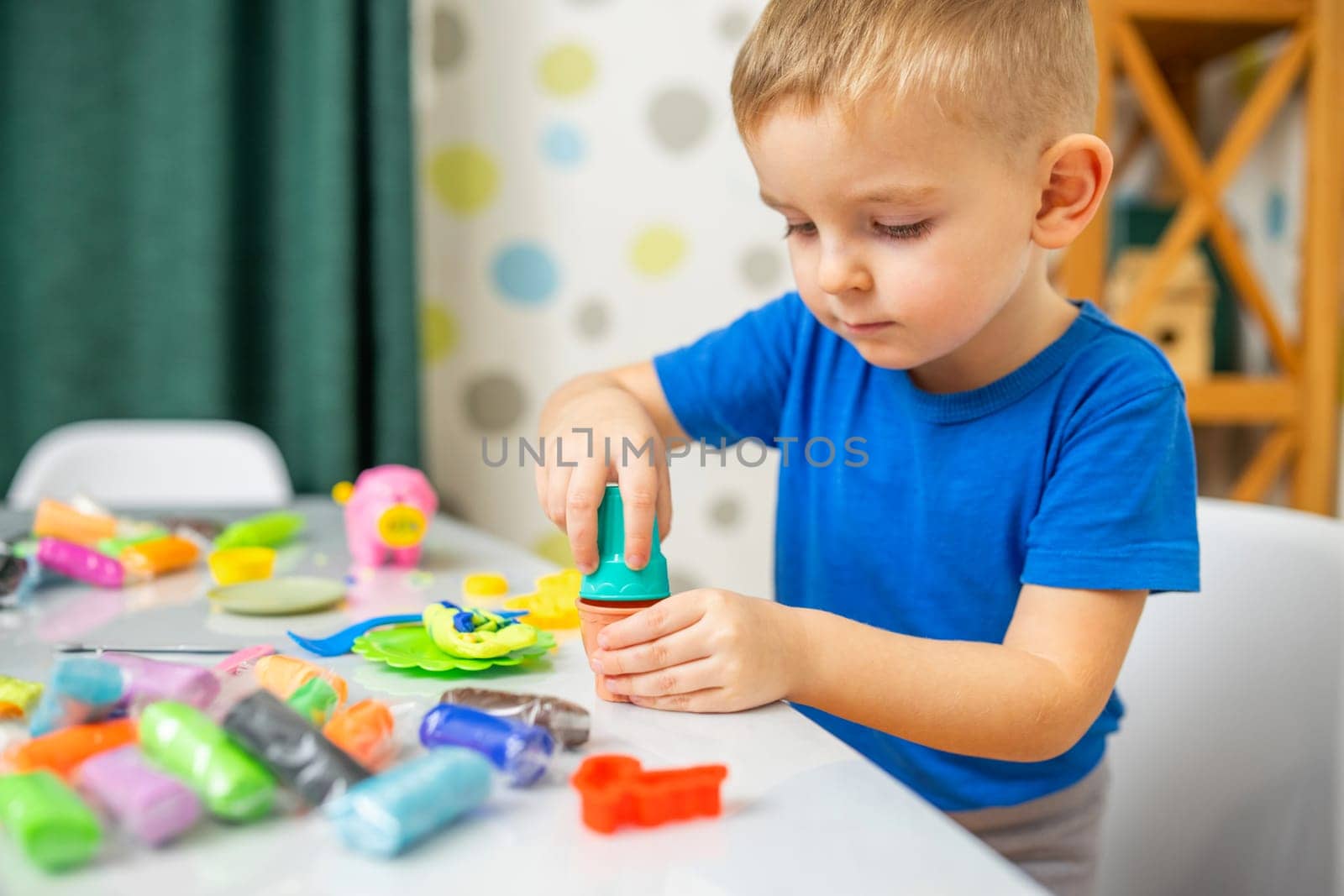 Kids playing with play dough. Cute children sitting at the table and plays with playdough. Creative leisure activity concept
