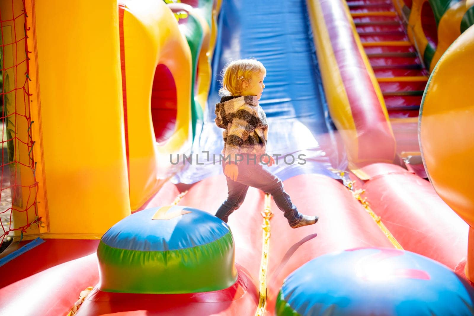 Happy kid having fun on colorful inflatable attraction playground. Child have fun and ride on the outdoor playground.