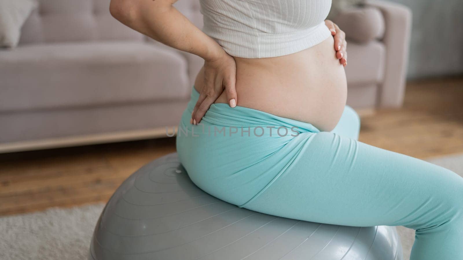 Caucasian pregnant woman suffers from back pain. Fitball training during pregnancy