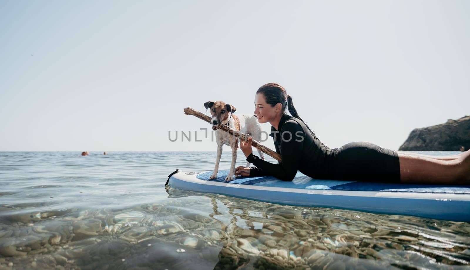 Sea woman sup. A happy positive woman in hat with family relaxing in sea, aerial back view of family on SUP board floating on calm water. Active lifestyle at sea. Summer vacation. Slow motion