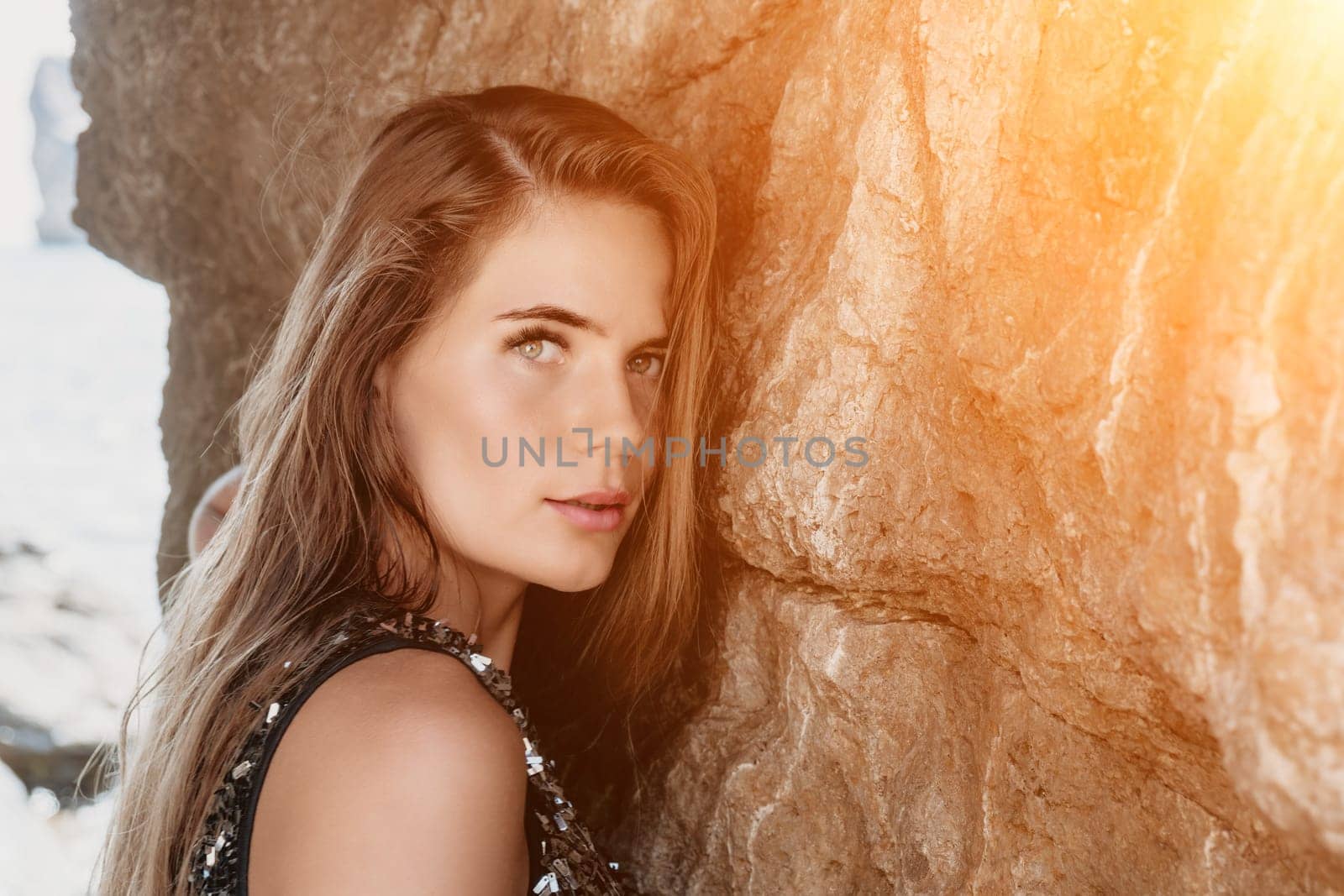 Woman travel sea. Young Happy woman in a long red dress posing on a beach near the sea on background of volcanic rocks, like in Iceland, sharing travel adventure journey