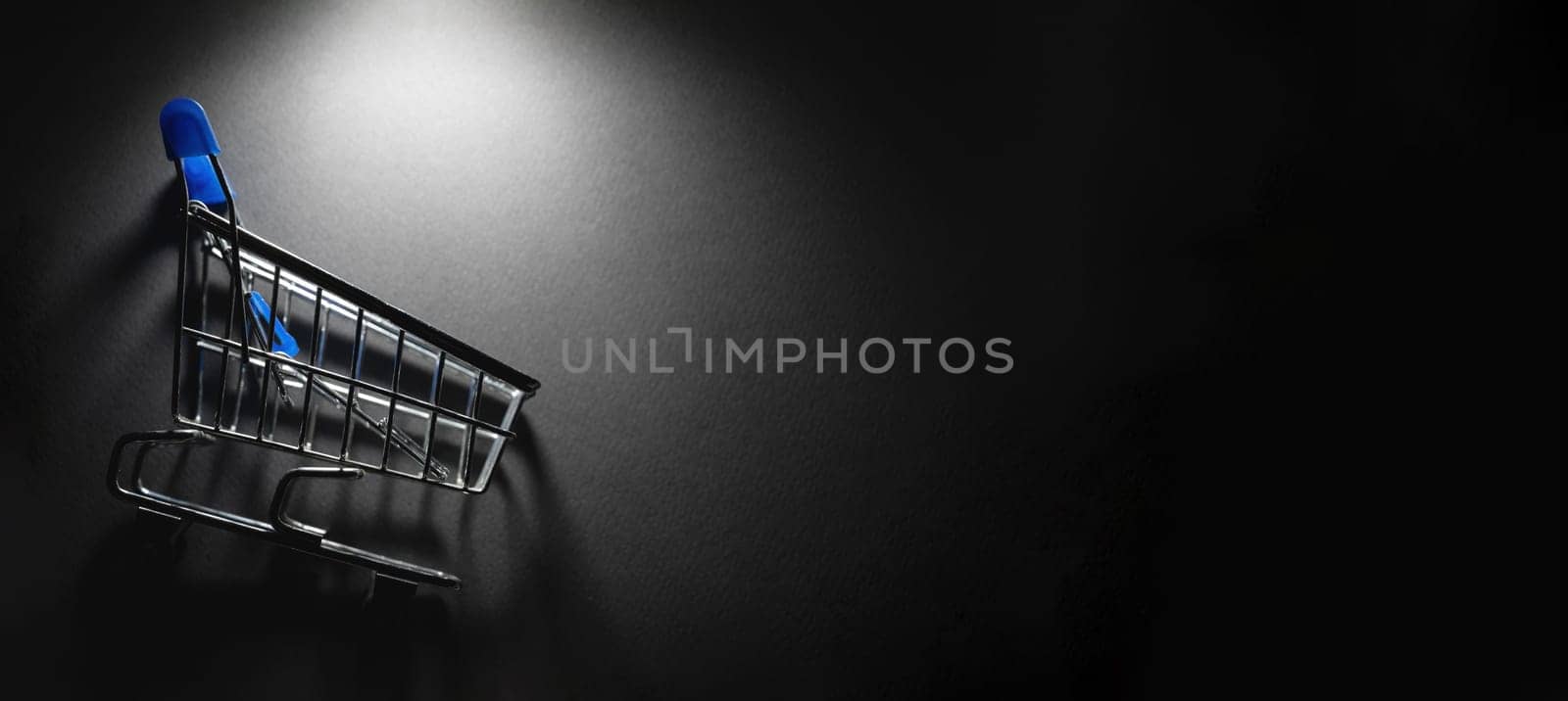 Supermarket cart with spotlight on it on a dark background