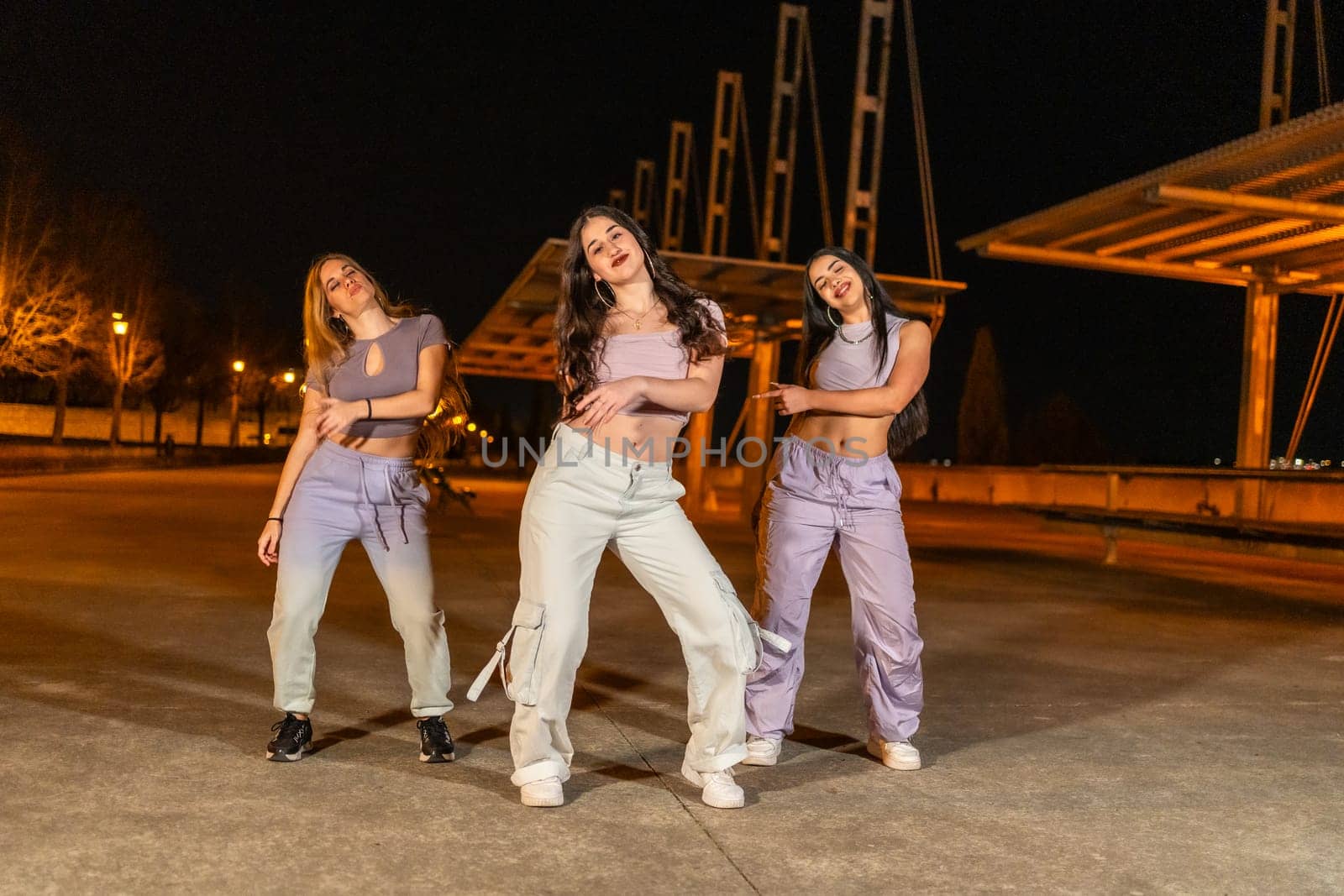 Three young female trap dancers performing in the street at night