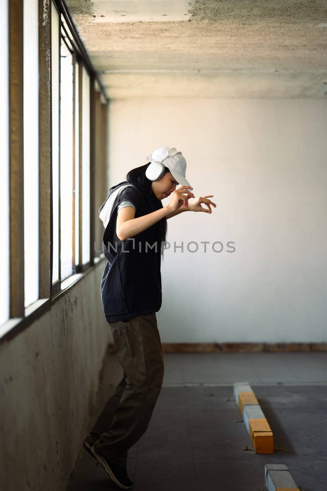 Young woman in headphone dancing Hip hop dance at parking garage. Active lifestyle concept by prathanchorruangsak