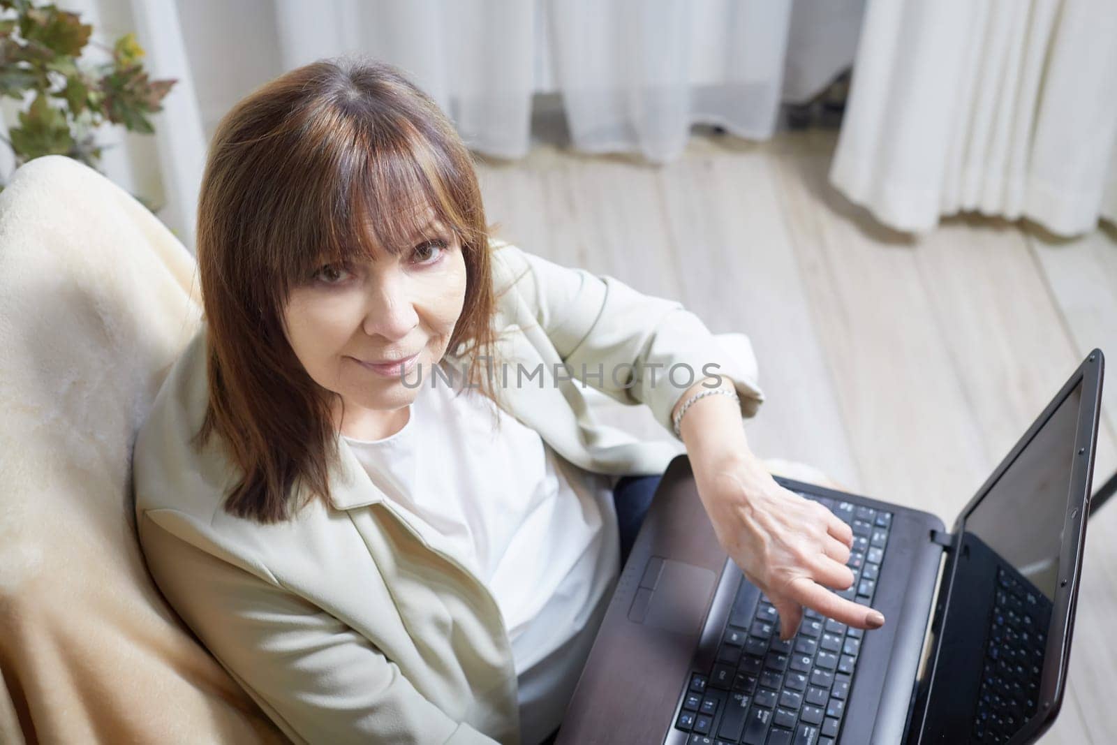 Elderly lady with a laptop in the room. A businesswoman is a leader, a manager is working. Grandma communicates with her grandchildren on the Internet