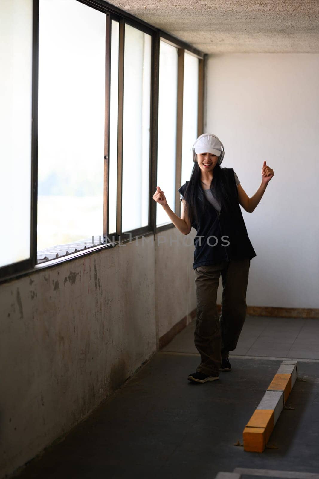 Happy young woman dancing Hip hop dance in parking garage. Hobby and active lifestyle concept by prathanchorruangsak