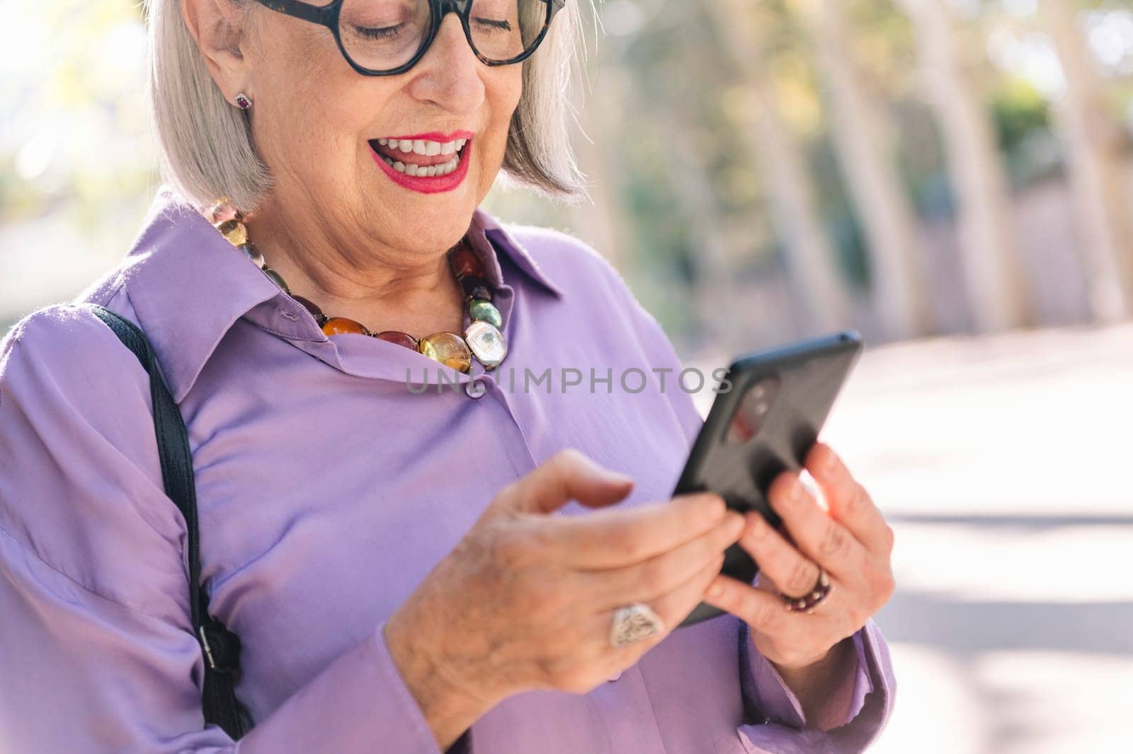 close up of a senior woman using mobile phone outdoors, concept of technology and elderly people leisure