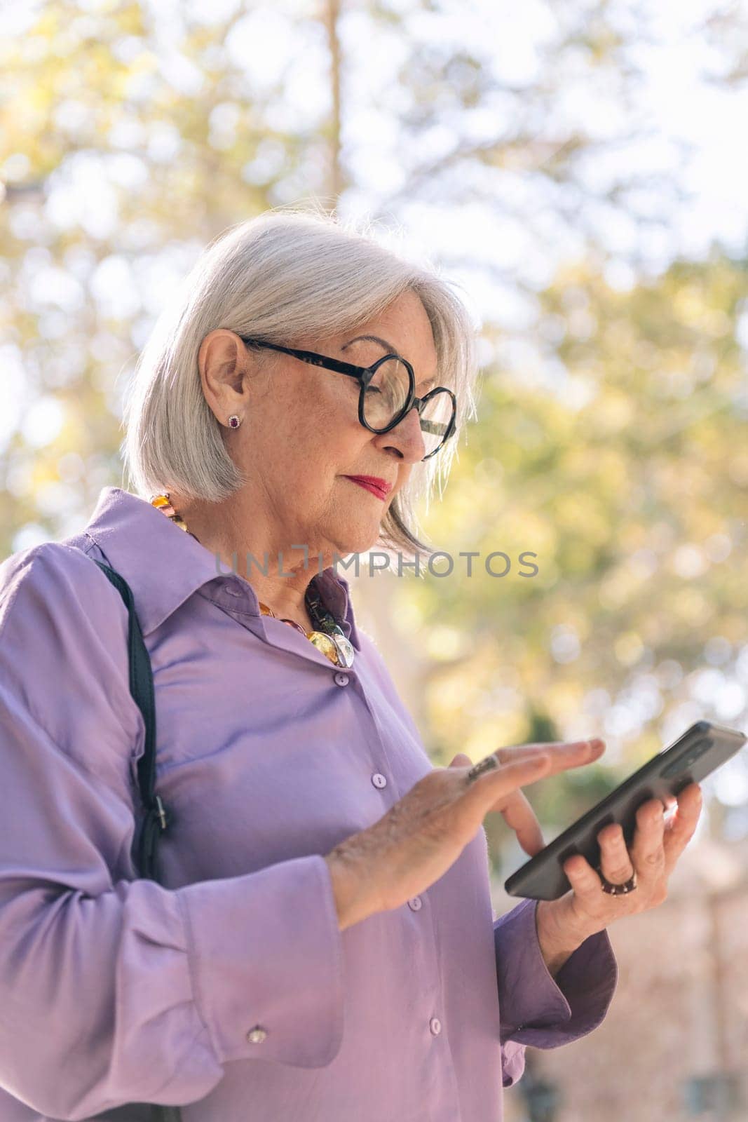 beautiful senior woman using mobile phone outdoors, concept of technology and elderly people leisure