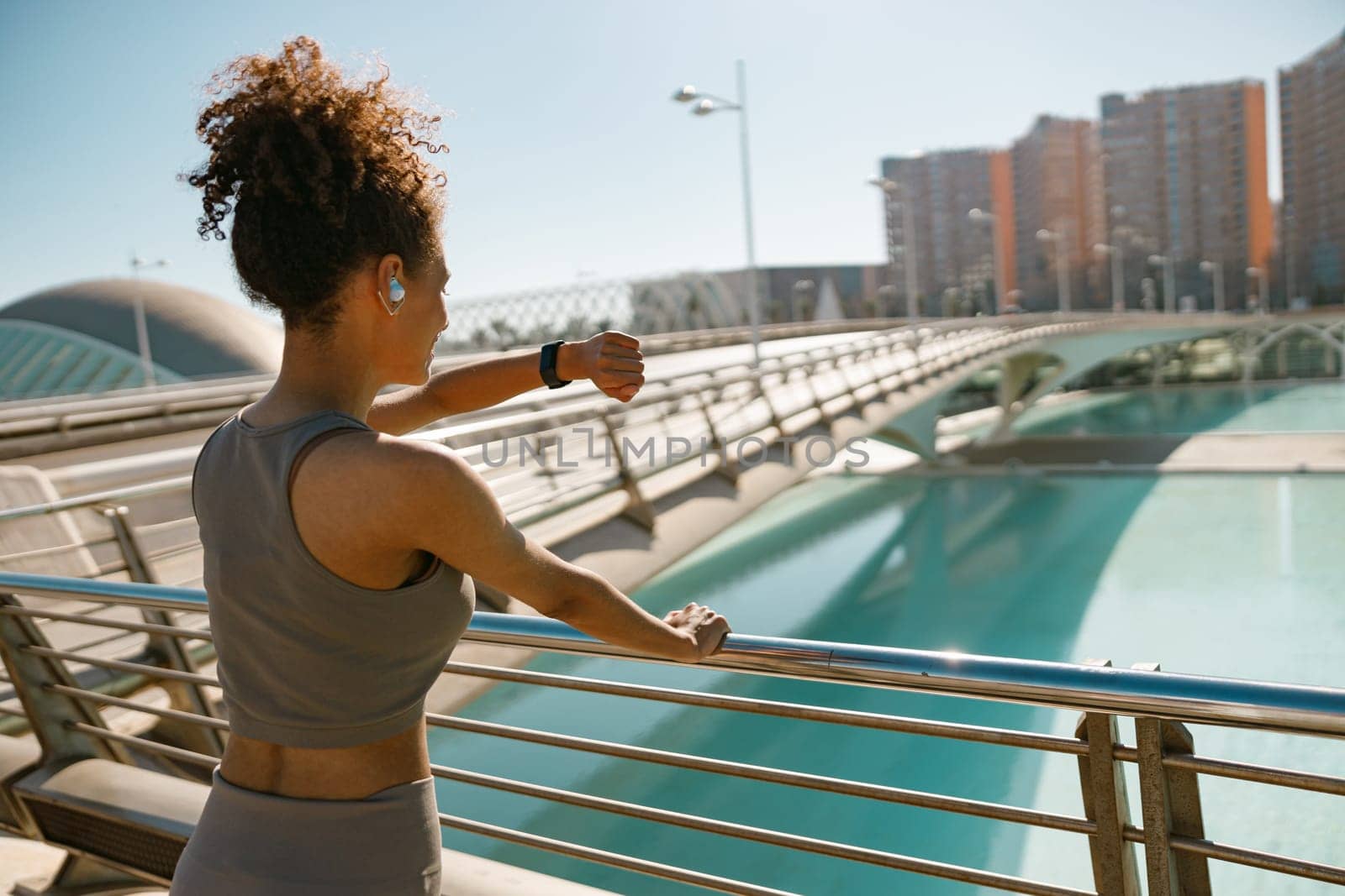 Back view of woman in sportswear looking on smartwatch before exercising. Outdoor sports concept by Yaroslav_astakhov