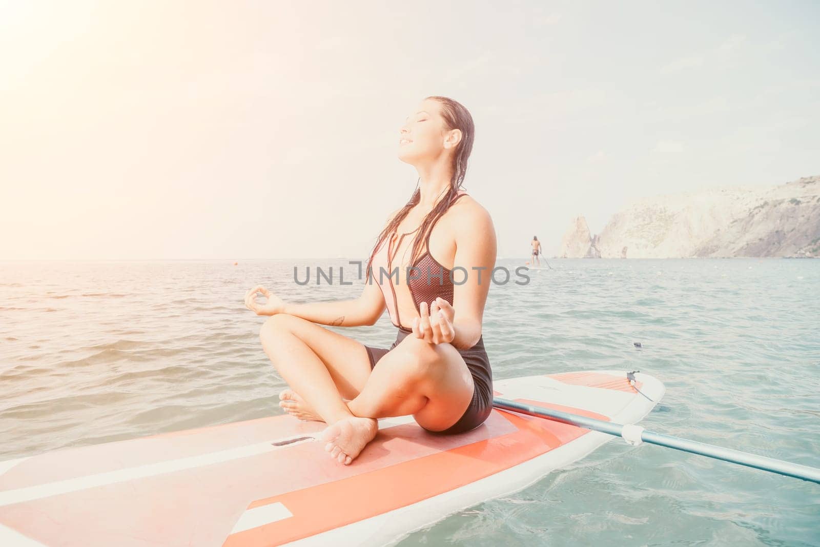 Woman sup yoga. Happy young sporty woman practising yoga pilates on paddle sup surfboard. Female stretching doing workout on sea water. Modern individual female outdoor summer sport activity