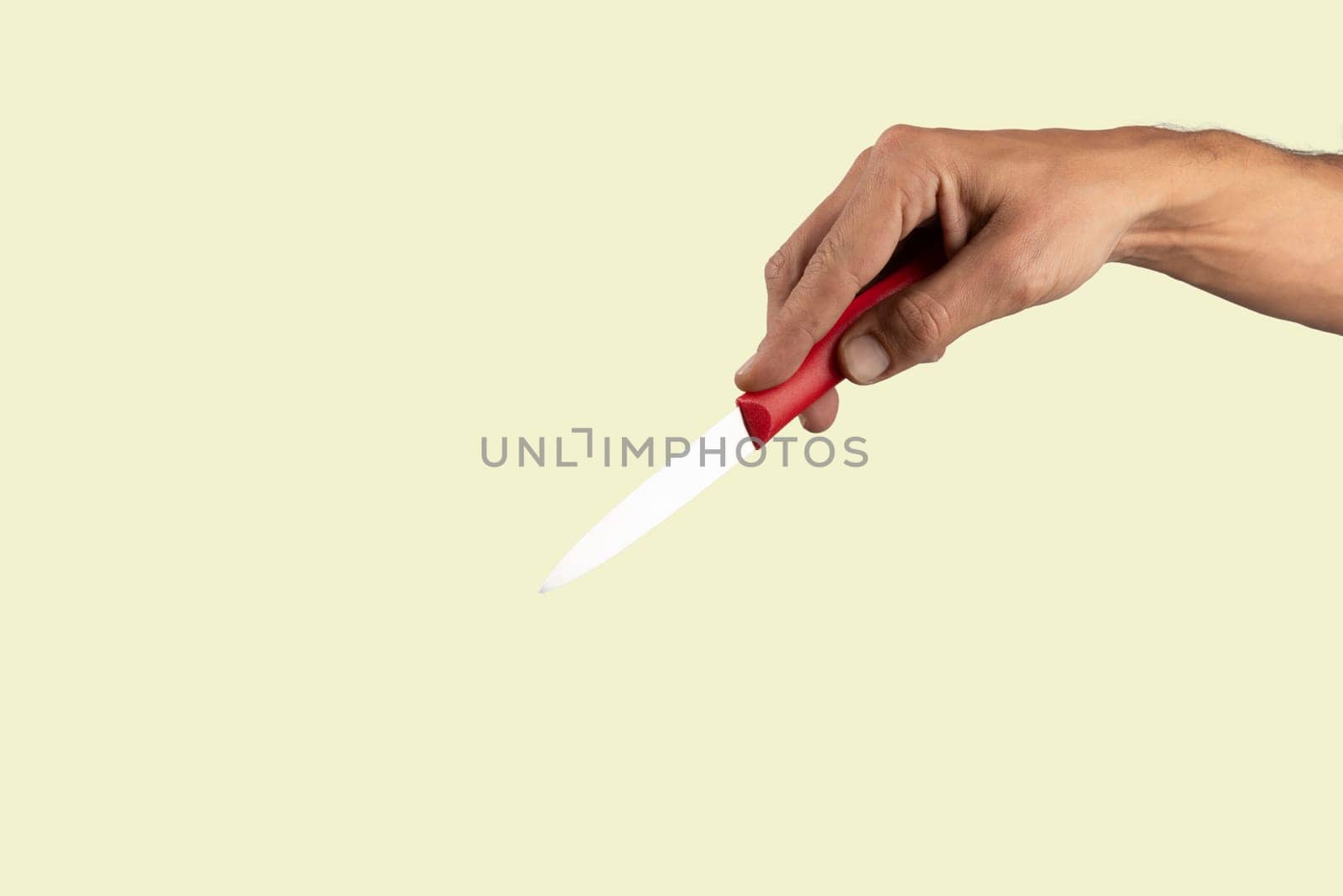 Black male hand holding a red cooking knife isolated on light green background. by TropicalNinjaStudio