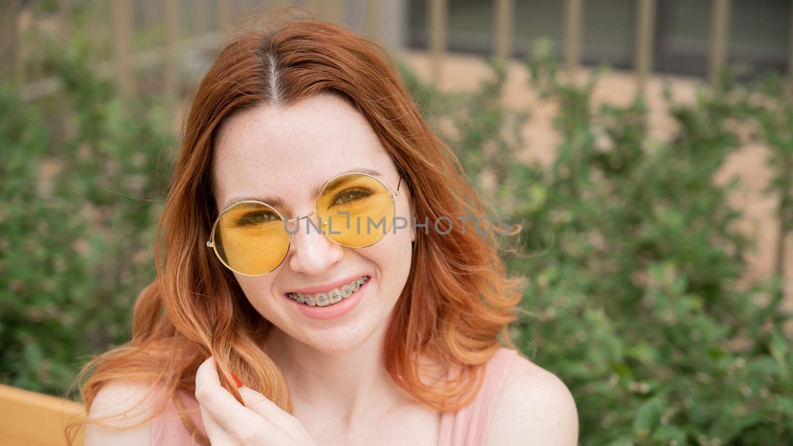 Beautiful young woman in yellow sunglasses smiling showing off braces on her teeth. by mrwed54