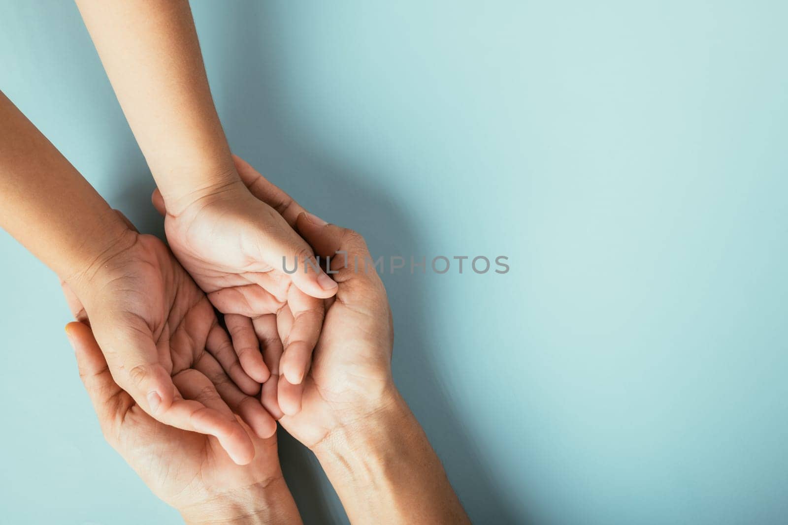 Close-up top view of family hands stack on isolated background. Parents and kid hold empty space symbolizing support and love on Family and Parents Day. by Sorapop
