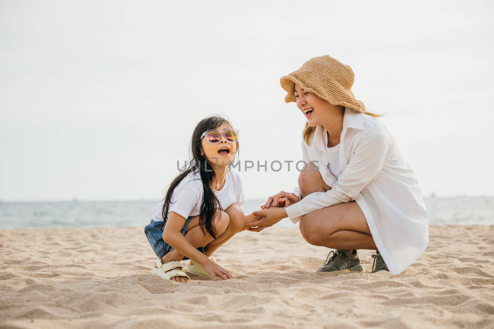 Sunset joy on the beach with a loving family. Mother and daughter happily sitting in the sand playing and bonding. Caribbean vacation filled with happiness togetherness and care