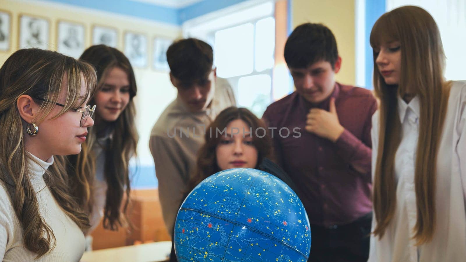 Students look at a globe of the starry sky in a classroom at school. by DovidPro