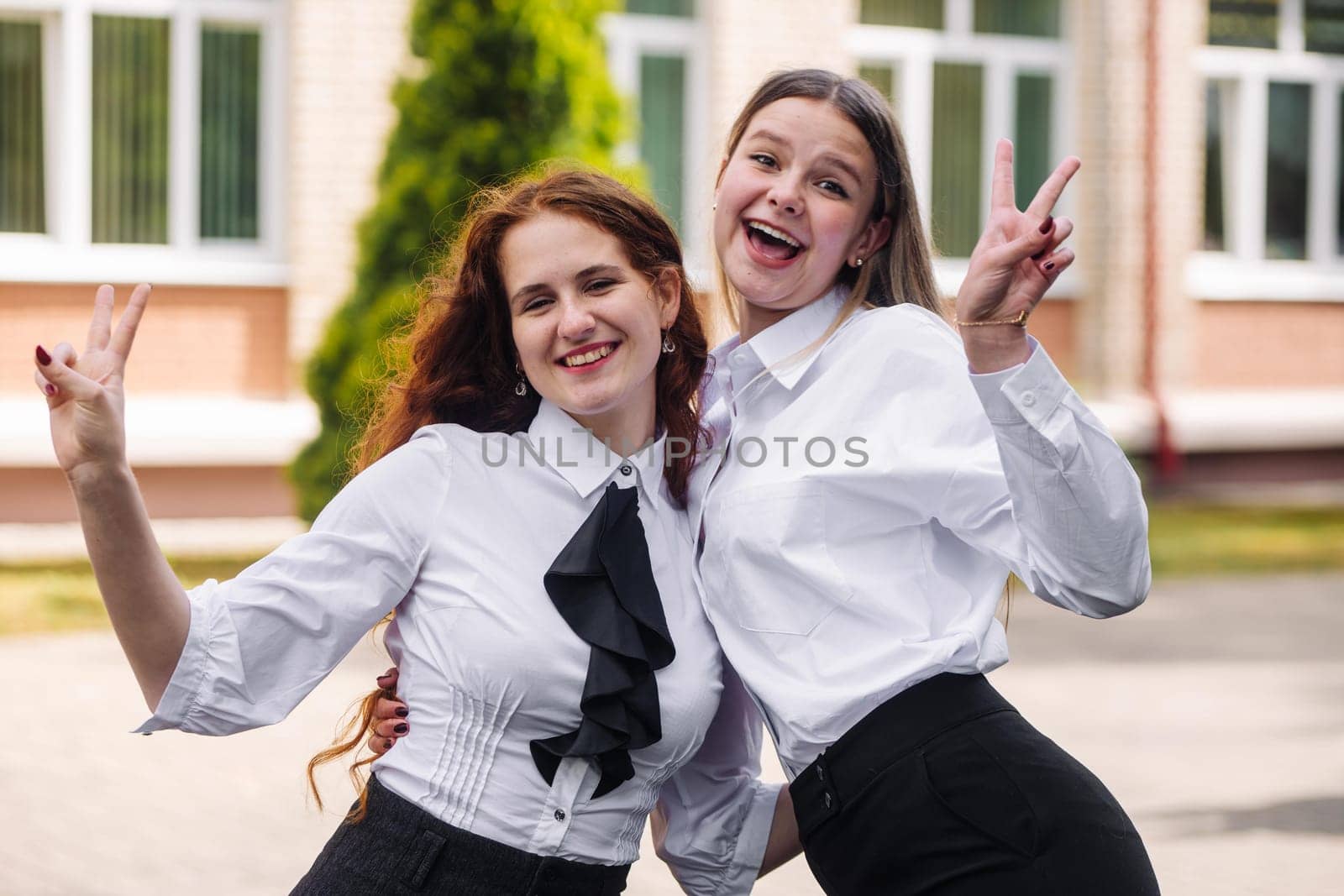 Portrait of two high school girls against the backdrop of the school. by DovidPro