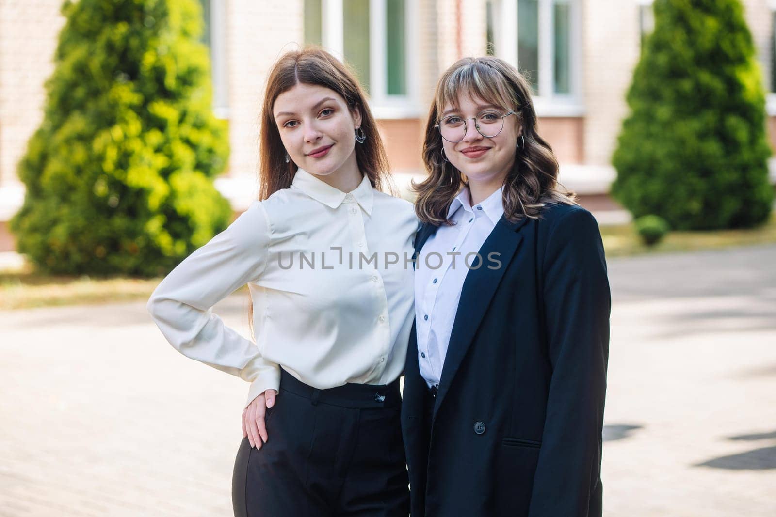 Portrait of two high school girls against the backdrop of the school. by DovidPro