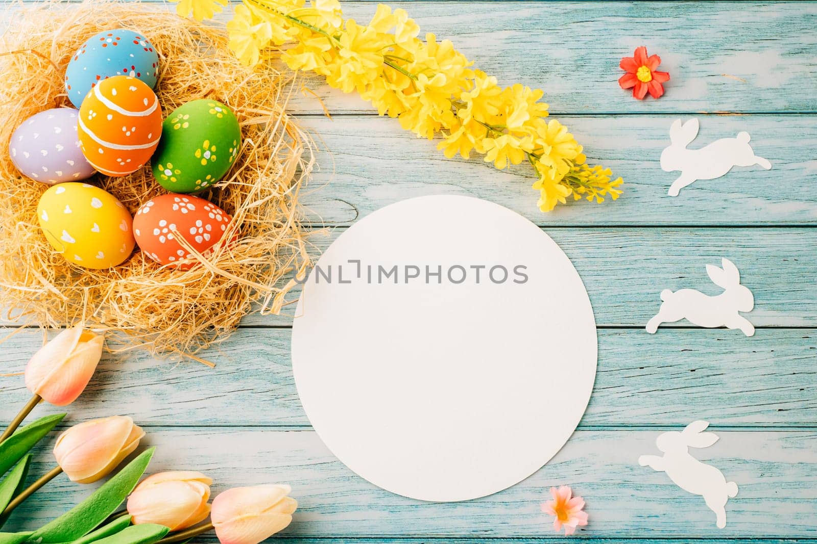 Happy Easter Day Concept. Flat lay of holiday banner background web design easter eggs in brown nest and blank paper circle on blue wooden background with empty copy space, celebration greeting card