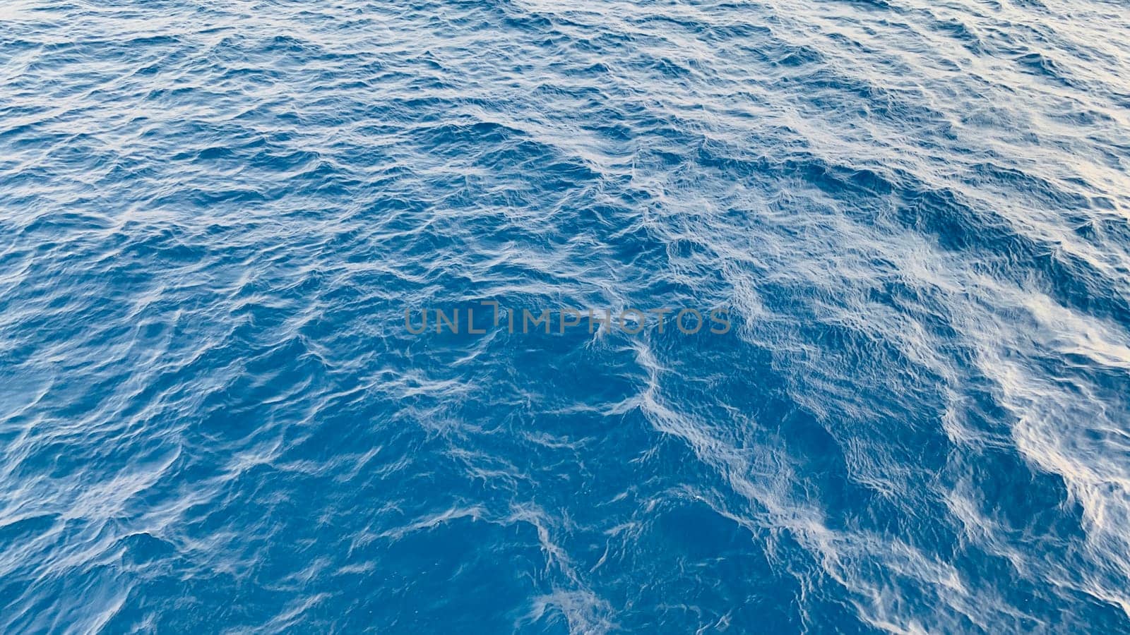 Photo of abstract blue color water wave, pure natural swirl pattern texture, background photography, Blue ocean water texture background. Surface of the sea in bali indonesia