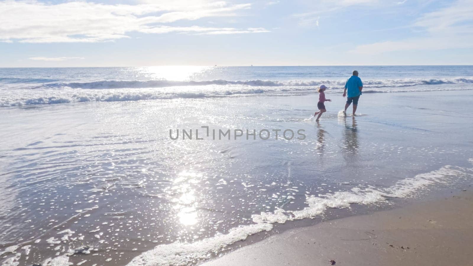 In California, a father and daughter share a serene winter walk along the deserted sands of El Capitan State Beach.