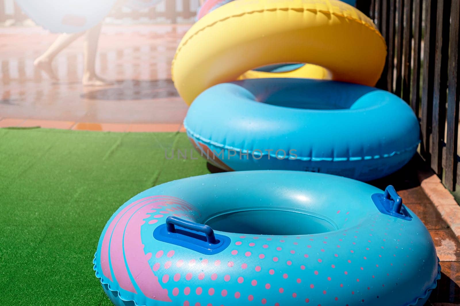 Blue and yellow inflatable wheels against background of wooden fence and nature on sunny day