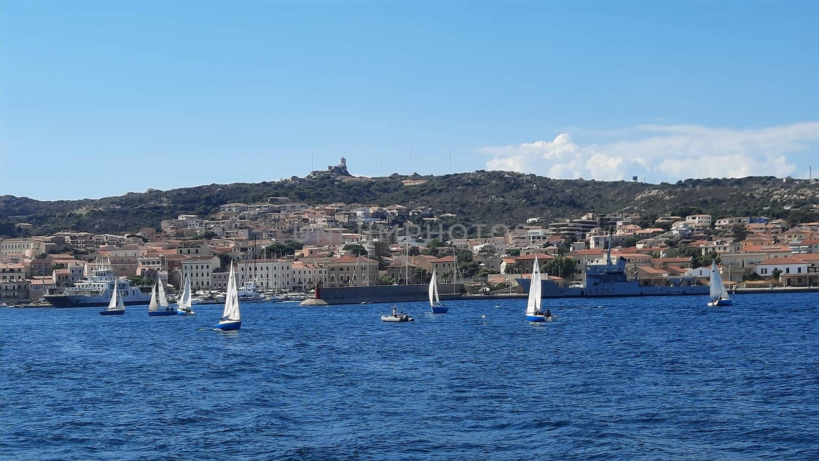 White yachts are anchored in a blue bay near Sardinia, Italy. Beautiful seascape with ships. A group of white yachts are moored in a sunny bay by Costin