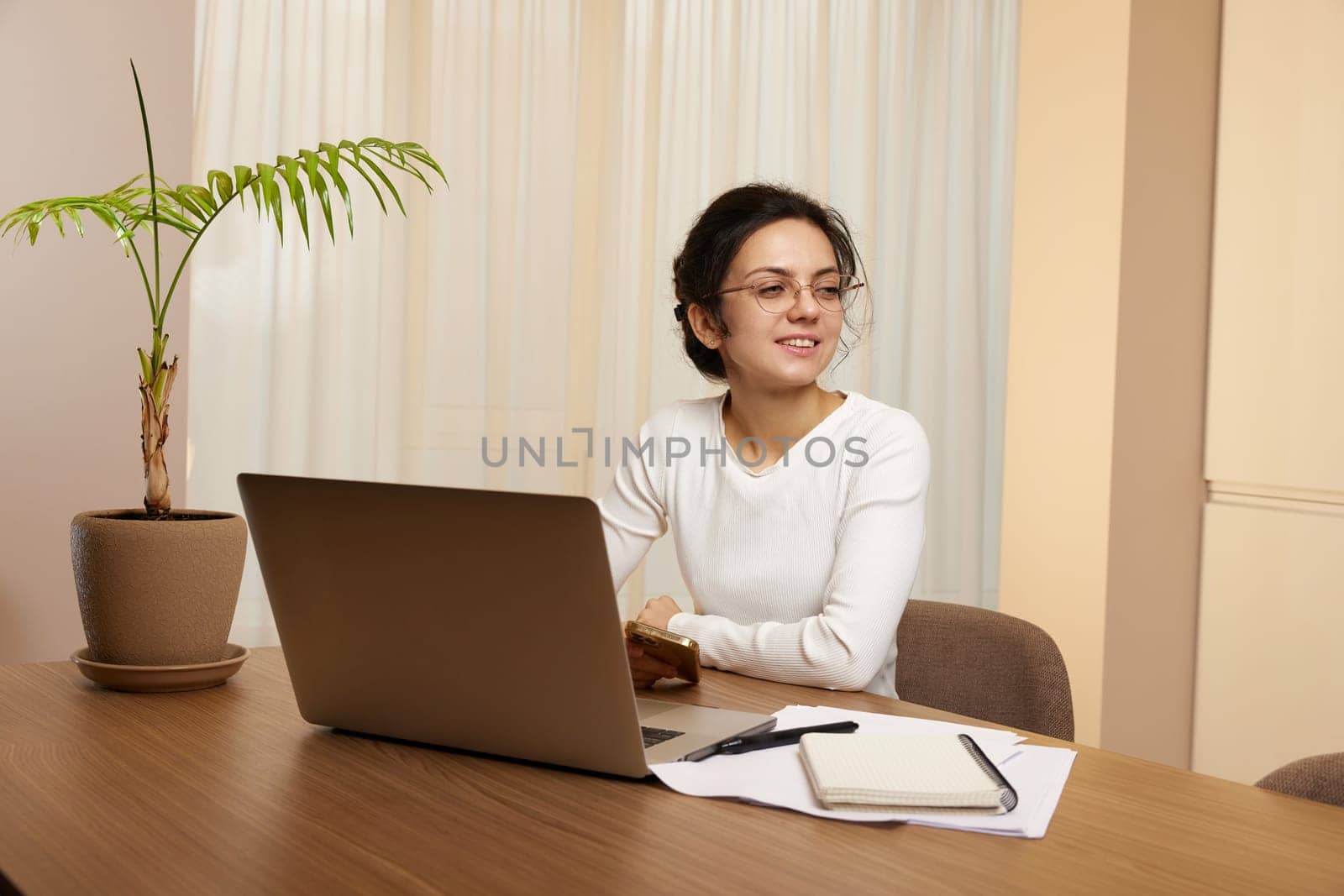 pretty woman in glasses using laptop and communicates with customer on internet at home