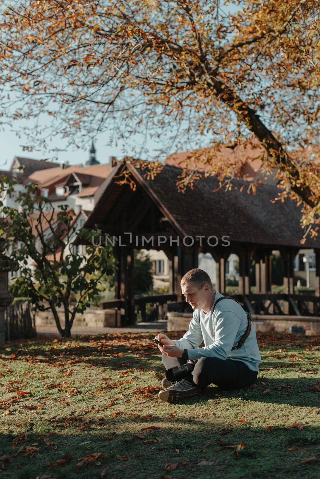 Professional photographer taking picture of beautiful autumn park. man professional photographer sit with camera in autumn park