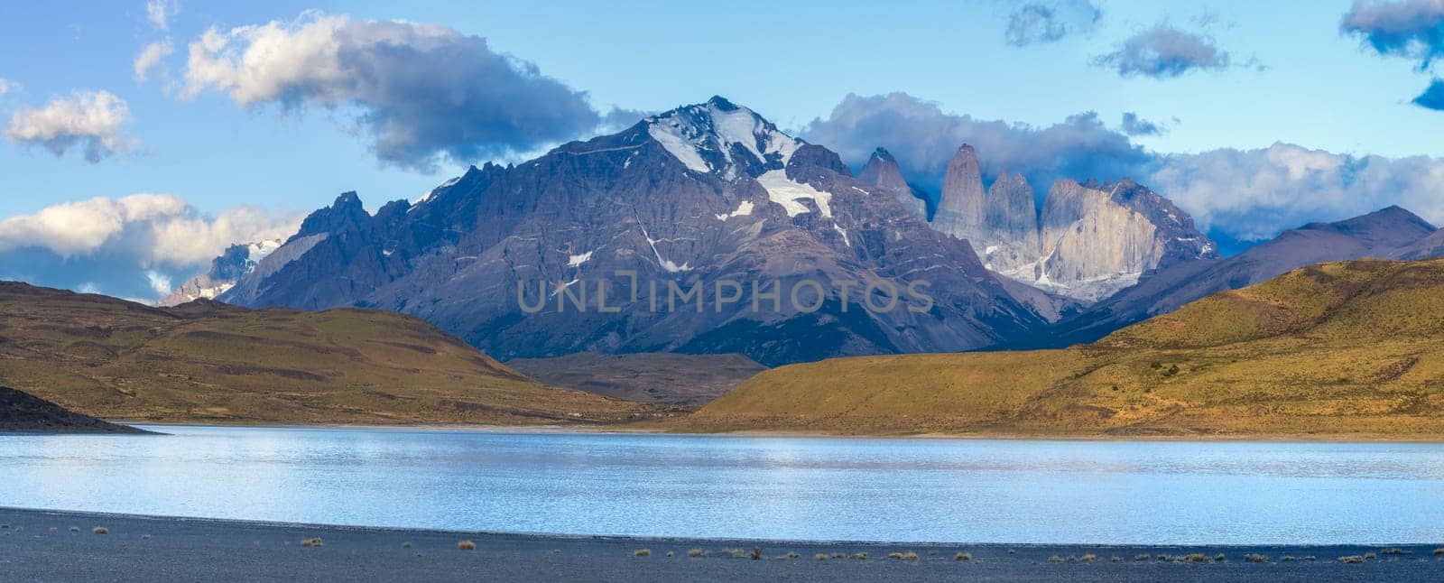 Serene lake with mountain backdrop captured in a panoramic view during golden hour, Torres del Paine