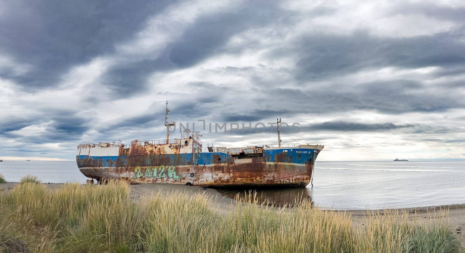 Abandoned rusted ship on a calm shore embodies quiet decay.