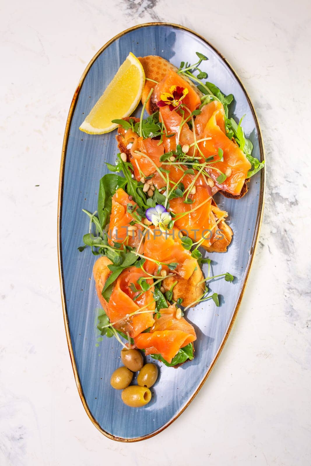 Delicious smoked salmon with lemon and microgreens served on a blue plate. Perfect for a healthy lunch or appetizer.