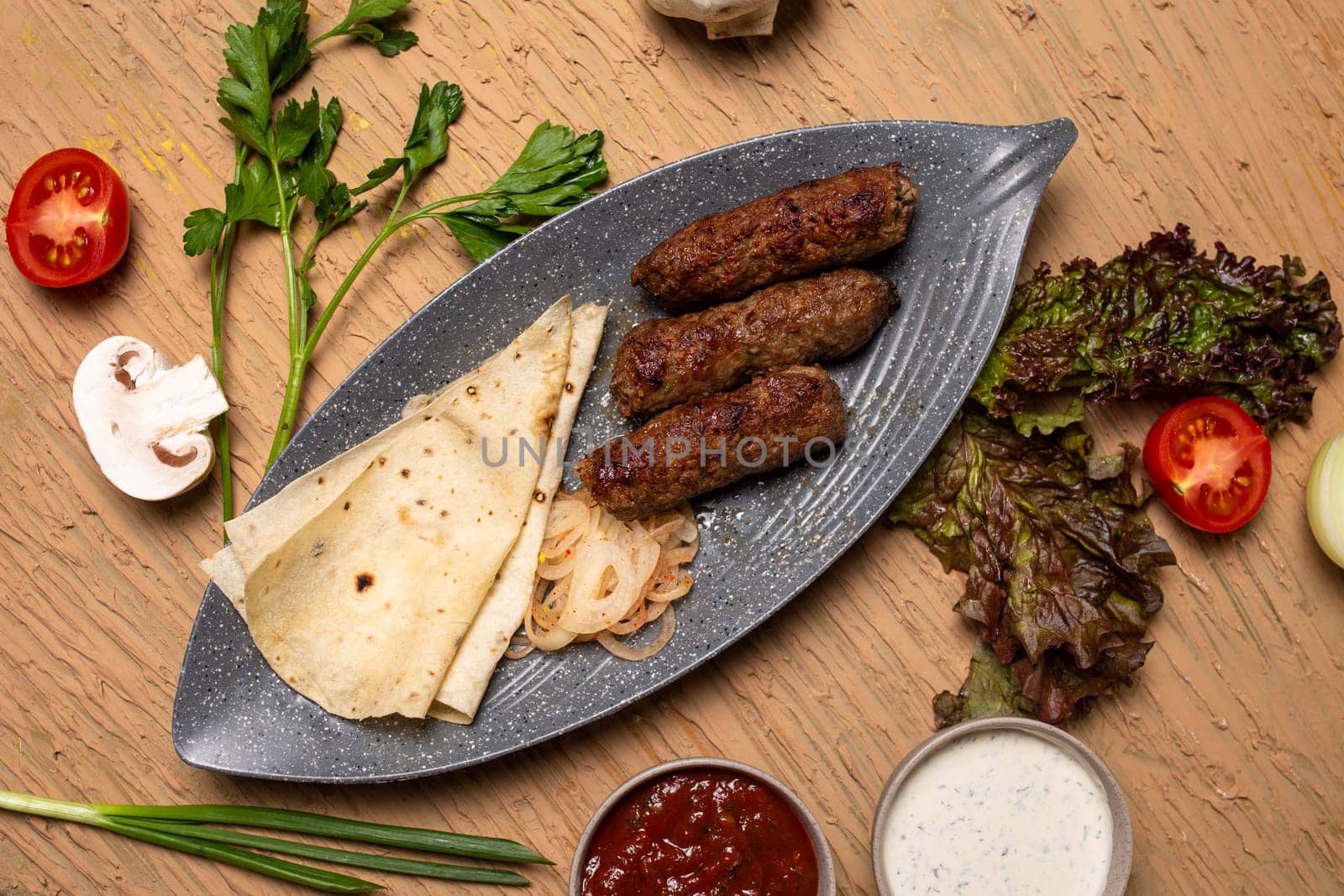 Top view of delicious kebabs lula lamb kebab with grilled vegetables and herbs on a wooden table. by Pukhovskiy