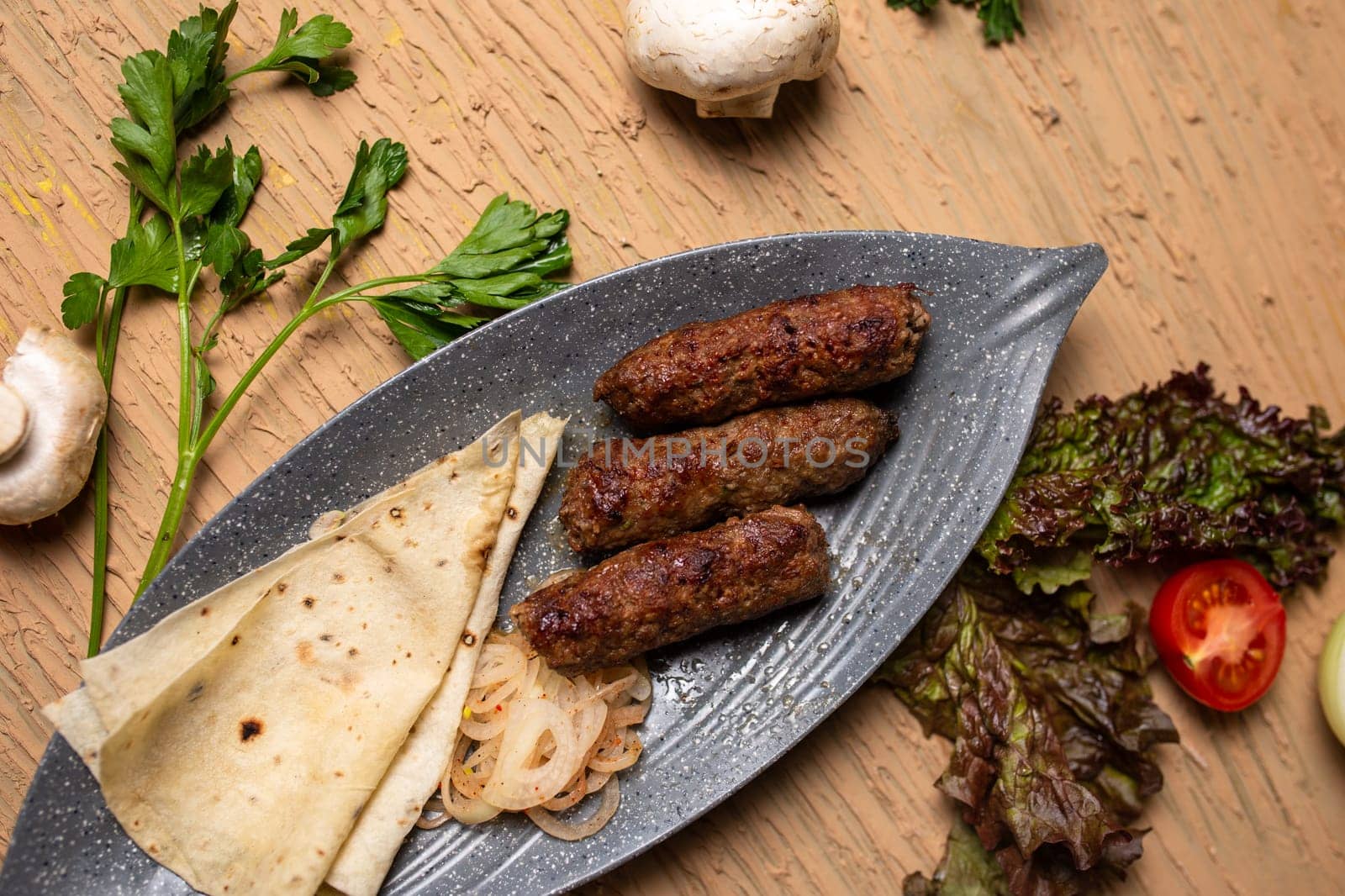 Top view of delicious kebabs lula lamb kebab with grilled vegetables and herbs on a wooden table. by Pukhovskiy