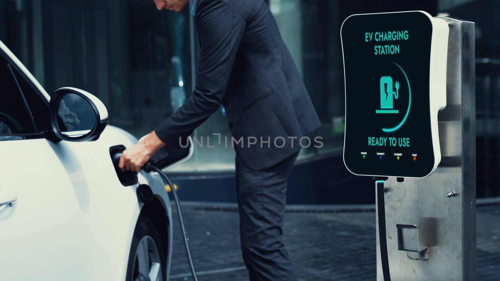 Businessman recharge his electric car from charging station at city center or public car park. Eco friendly rechargeable car using alternative clean energy in urban city lifestyle.Peruse