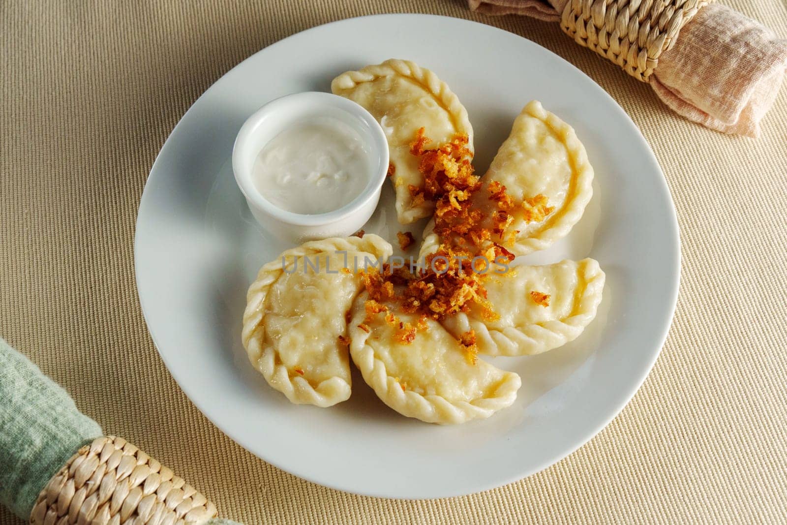 White plate showcases an array of delectable dumplings, perfectly paired with a luscious bowl of flavorful dip. by darksoul72