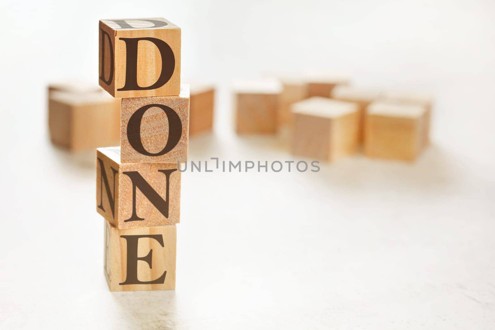 Four wooden cubes arranged in stack with word DONE on them, space for text / image at down right corner