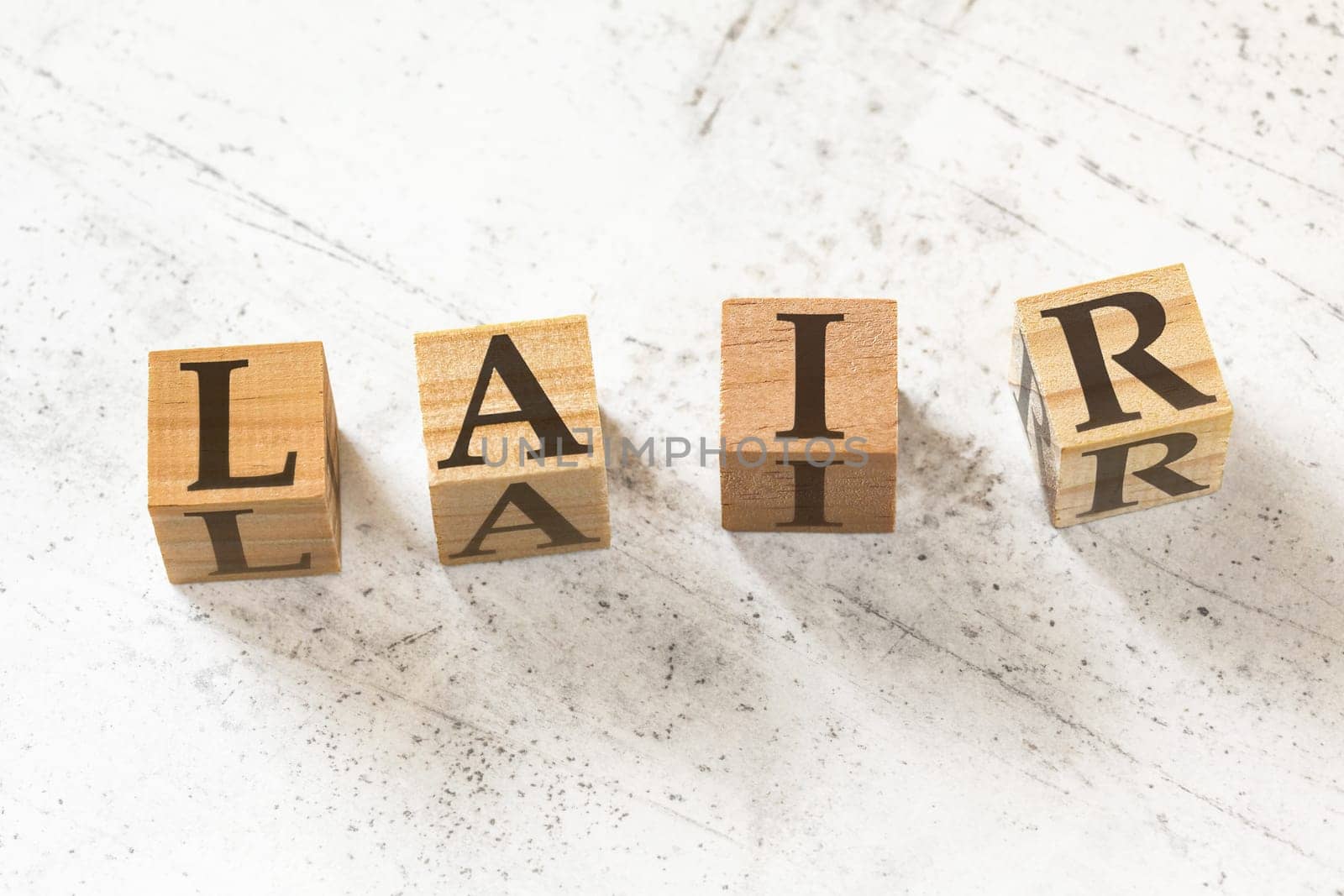 Four wooden cubes with letters LAIR (meaning Listen Acknowledge Identify Reverse) on white working board. by Ivanko