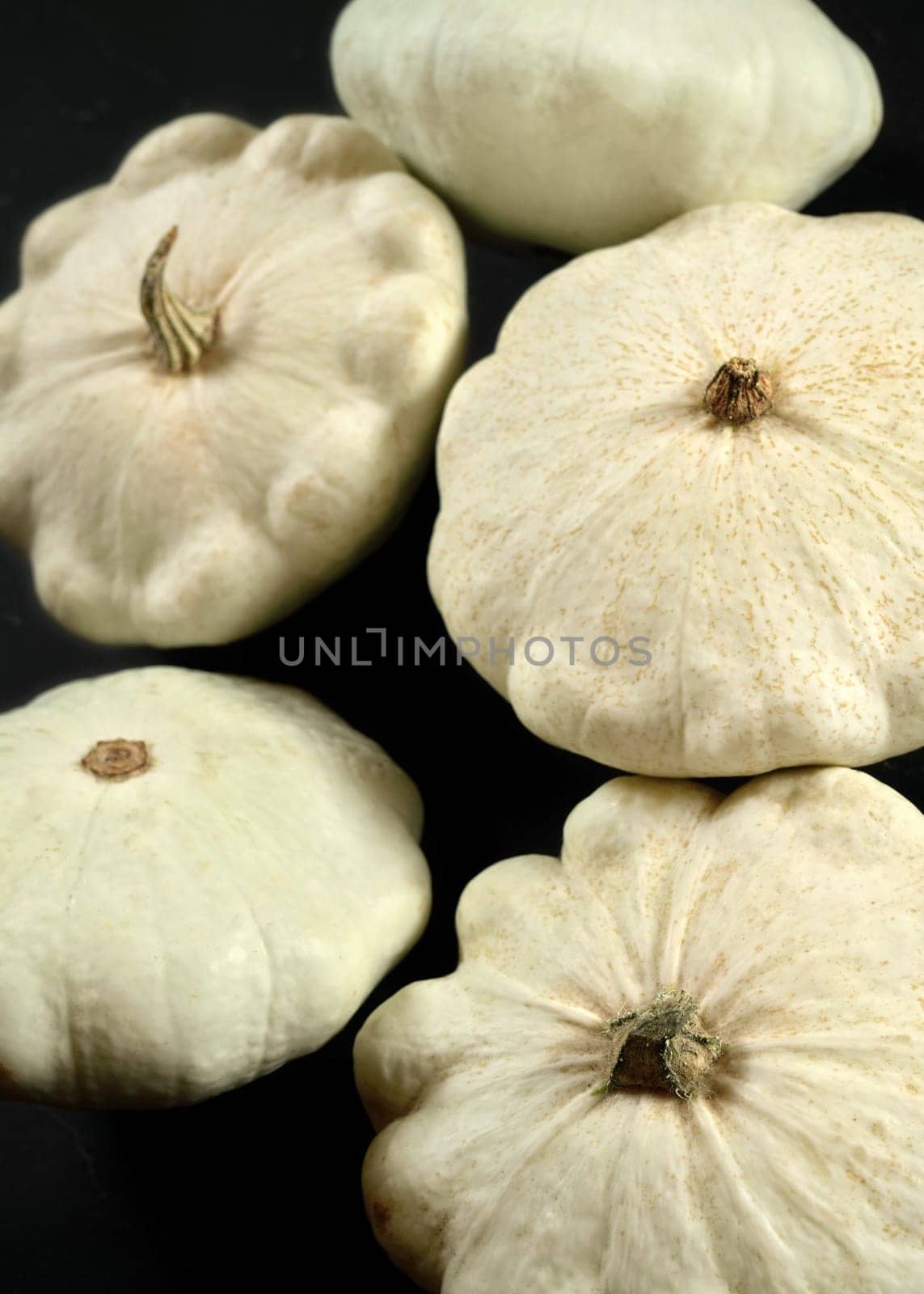 White pattypan squash pumpkins on black board