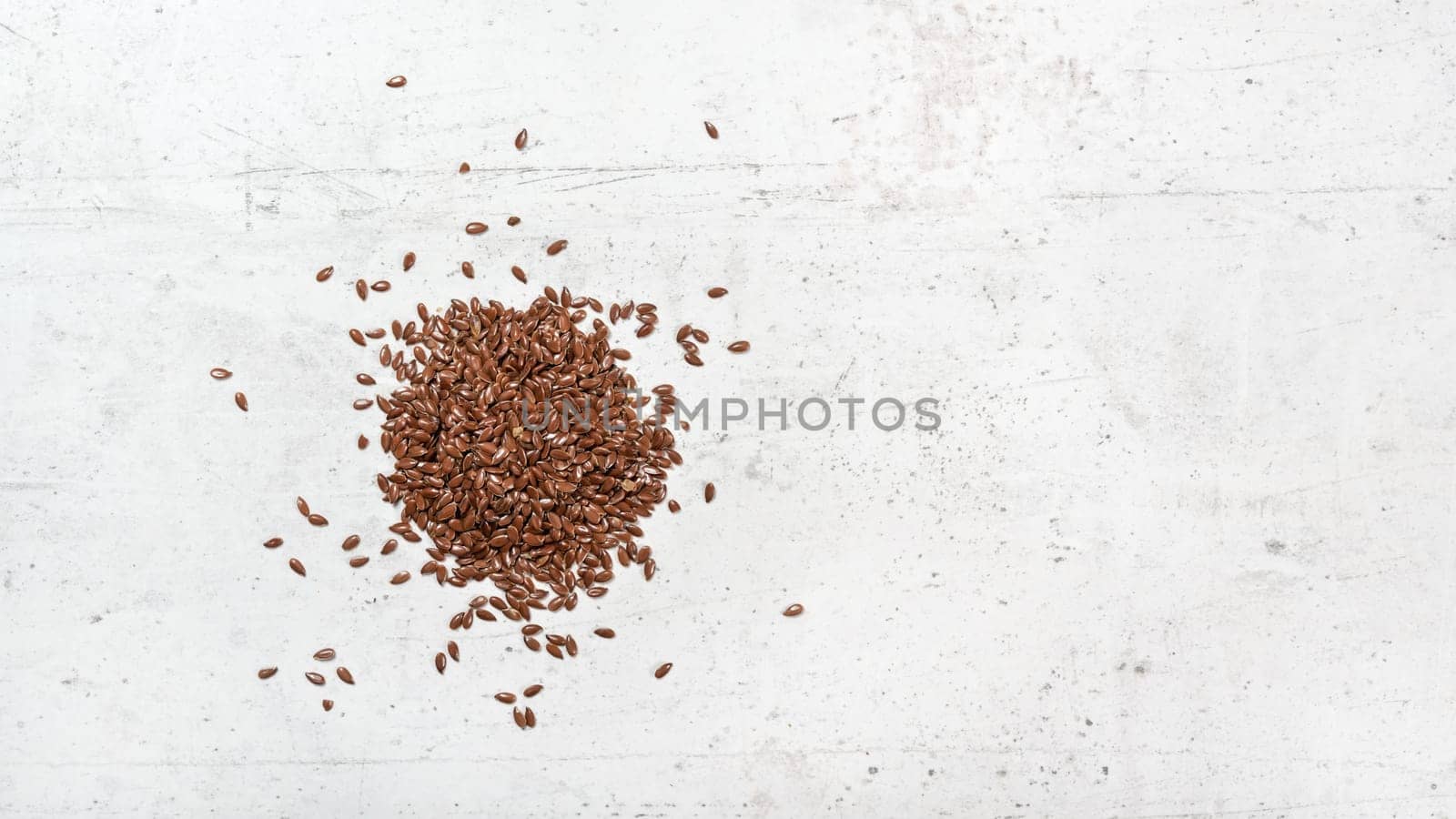 Flax seeds on white stone like board, view from above, banner with space for text right side