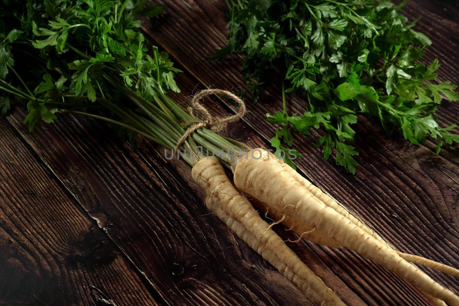 Bunch of parsley roots with green leaves on dark wooden rustic board