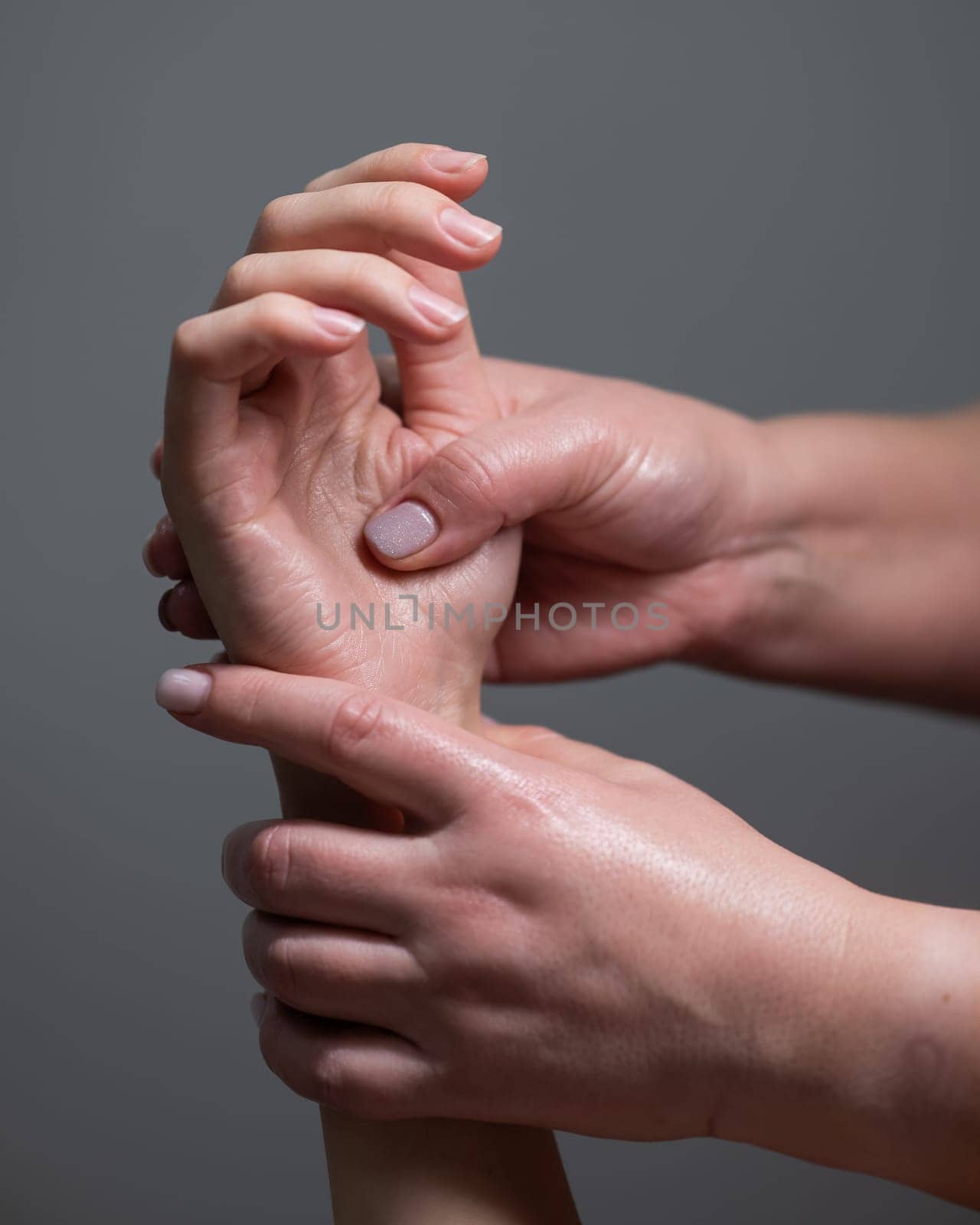 The masseuse massages the client's palms. Close-up of hands at a spa treatment. Vertical photo