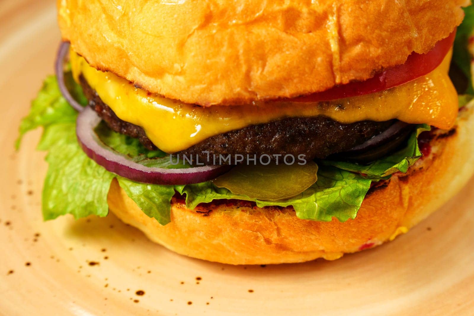 Cheeseburger topped with lettuce and various toppings placed on a plate, ready to be enjoyed.