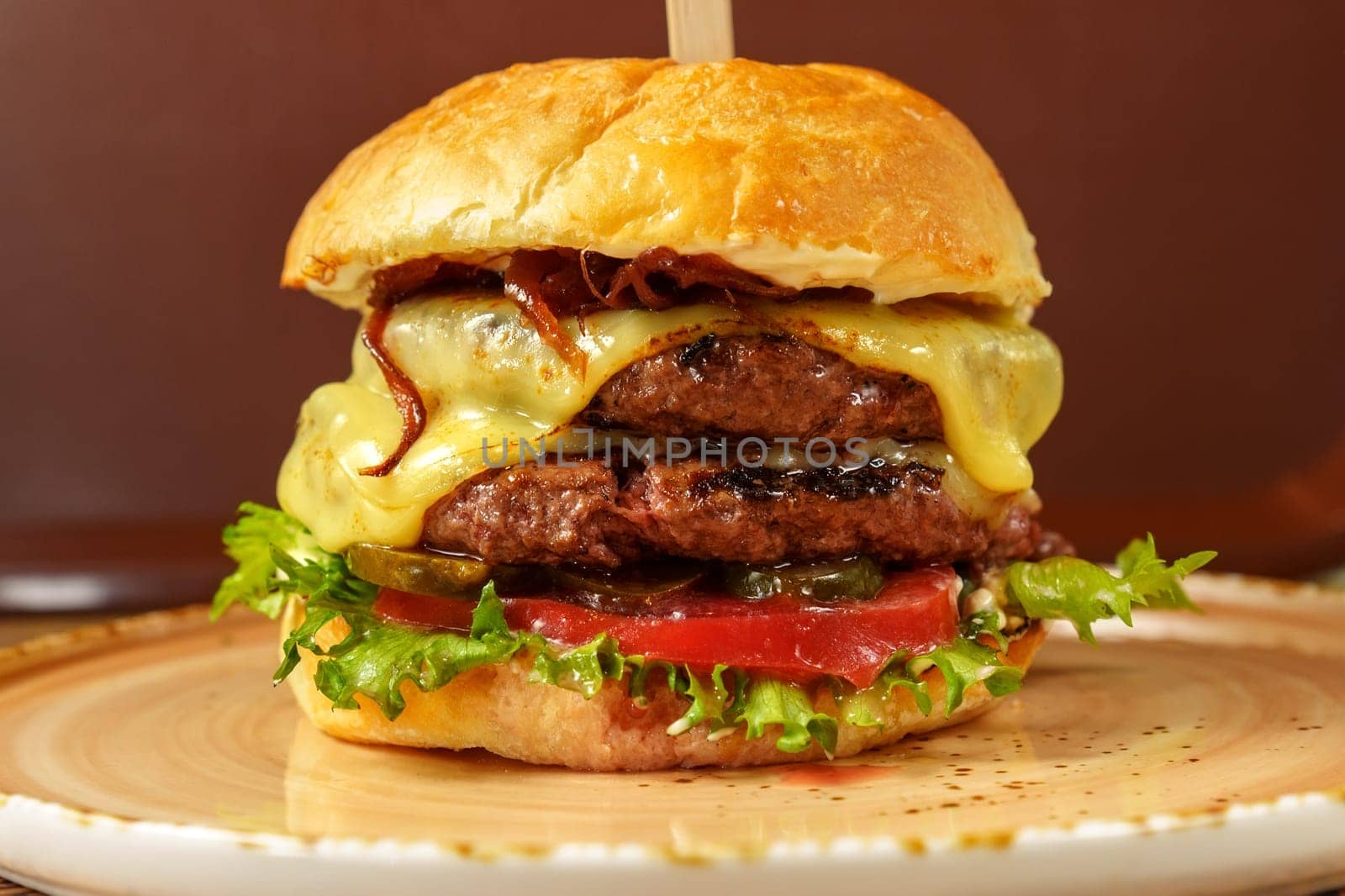 Cheeseburger topped with fresh lettuce and tomato on a sesame seed bun, ready to be enjoyed.