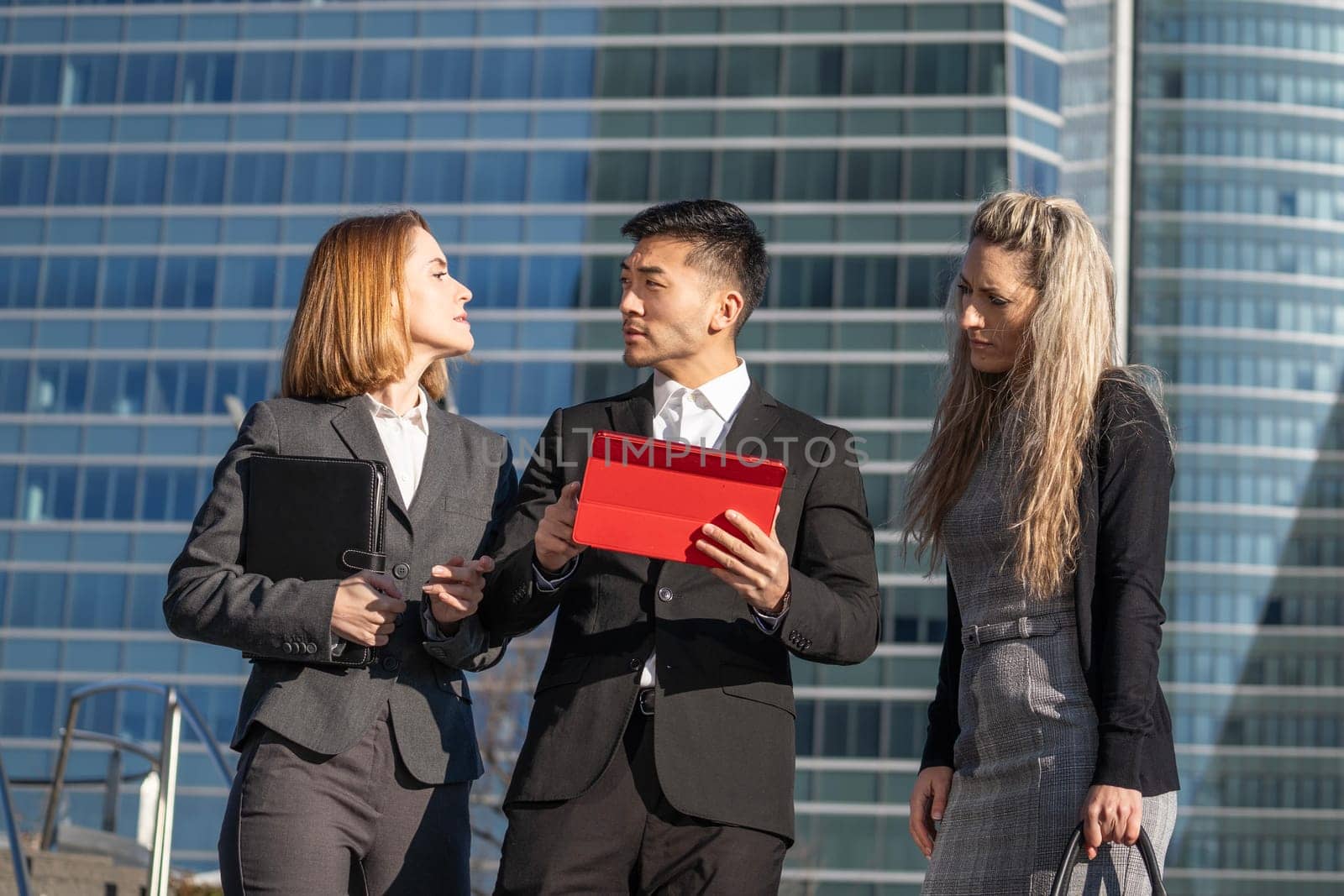 Business man and women teamwork talking while standing outdoors in an office area by papatonic