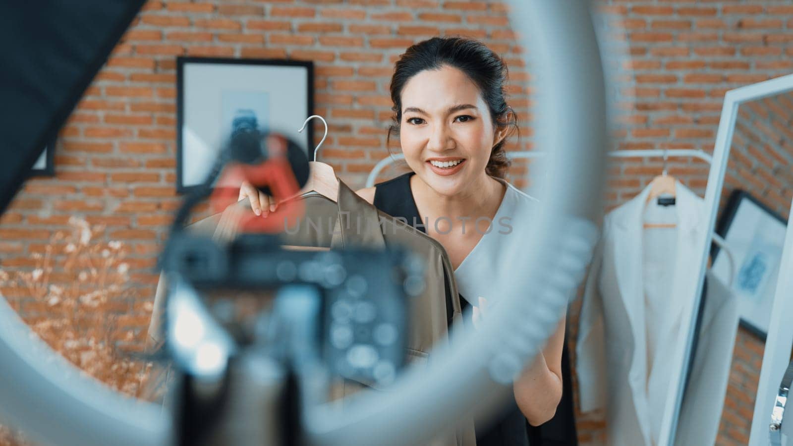 Woman influencer shoot live streaming vlog video review clothes social media or blog. Happy young girl with apparel vivancy studio lighting for marketing recording session broadcasting online.