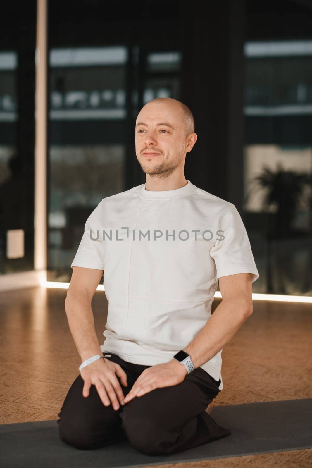 An athletic young man does exercises in the fitness room. A professional guy does yoga in the gym by Lobachad