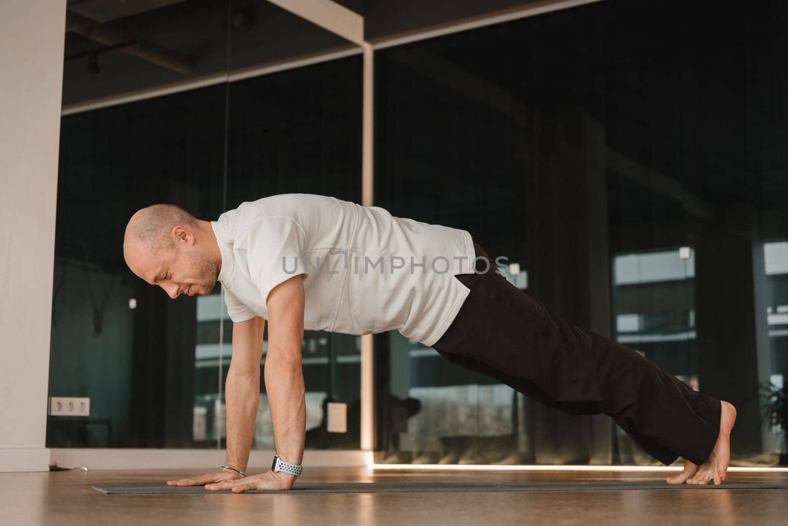 An athletic young man does exercises in the fitness room. A professional guy does yoga in the gym by Lobachad