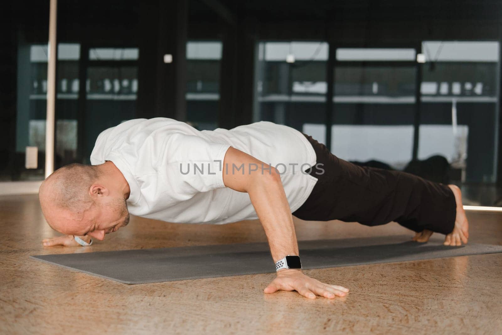 An athletic young man does exercises in the fitness room. A professional guy does yoga in the gym by Lobachad