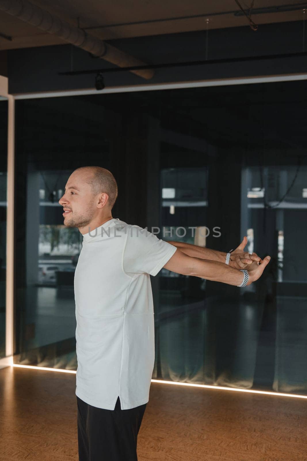 An athletic young man does exercises in the fitness room. A professional guy does yoga in the gym by Lobachad